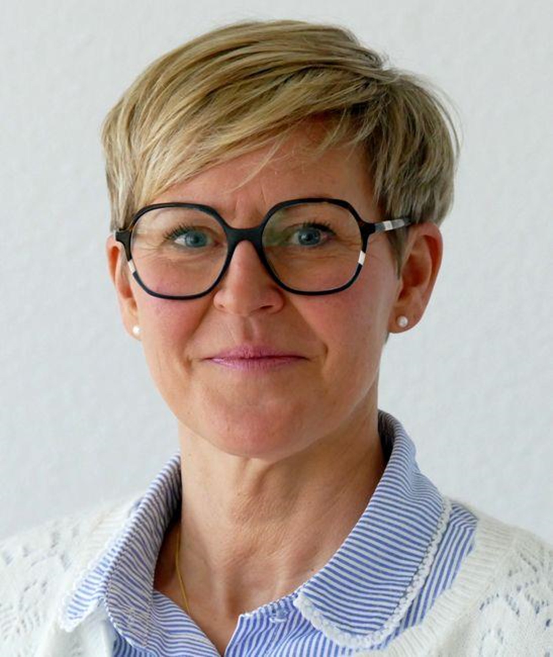 Portraitfoto einer Frau mir dunkler Brille und kurzen, blonden Haaren